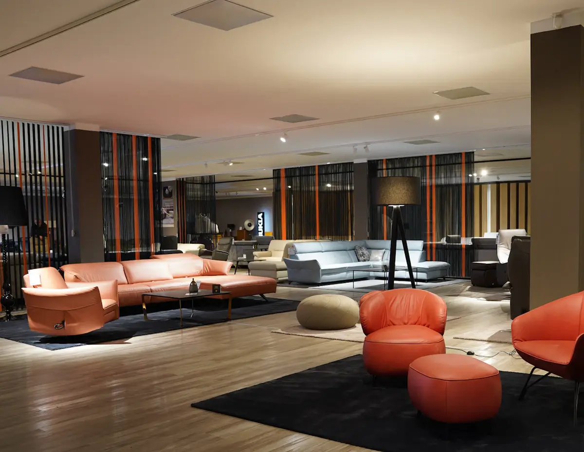 Inside a large furniture showroom with sofas, armchairs and ottomans laid out on wooden floors