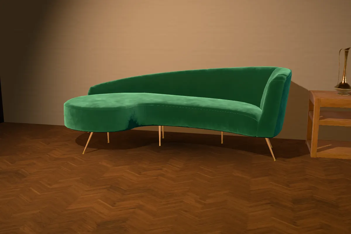 The finished emerald velvet sofa on teak legs in a warm lit room, beside a side table with a brass ewer
