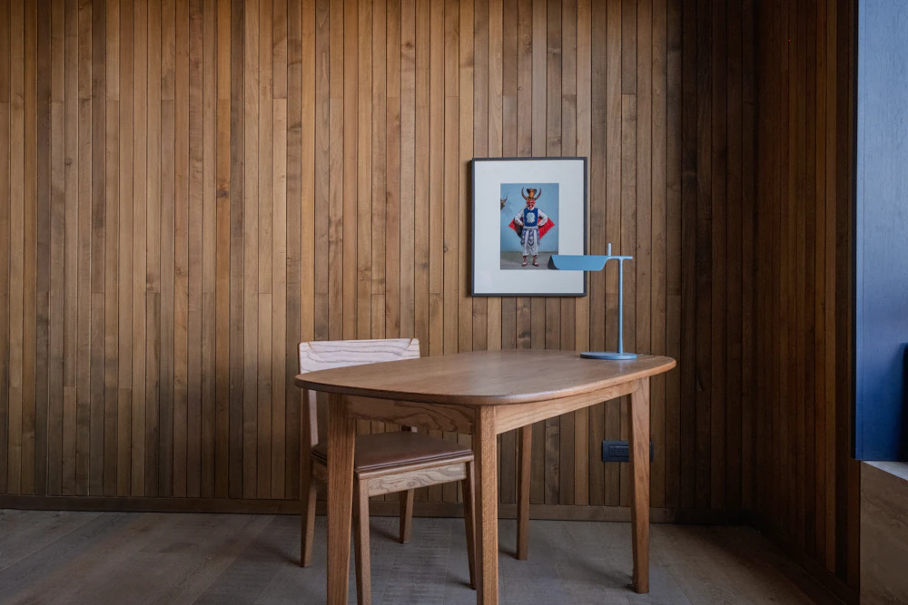 A wooden study table and chair in a room with wood panelled walls