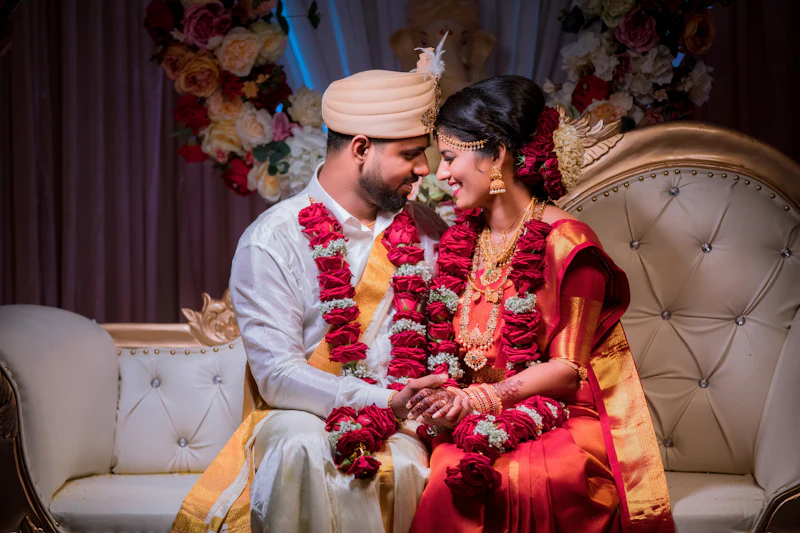 Bride and groom in silk and garlands, sitting together on the stage