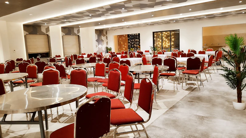 Bright party hall with round tables and red chairs