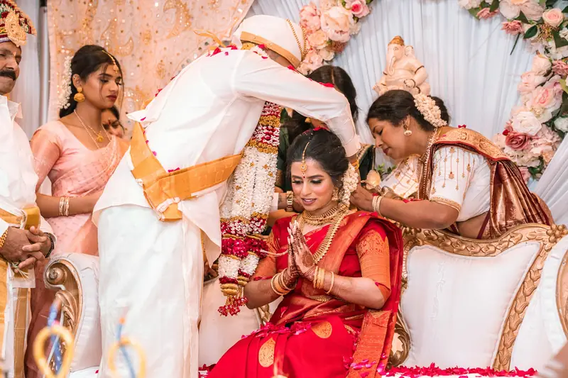 The groom ties the thali as the bride sits with folded hands, family close around them