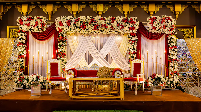 Reception stage with red and white flower arches and a sofa for the couple
