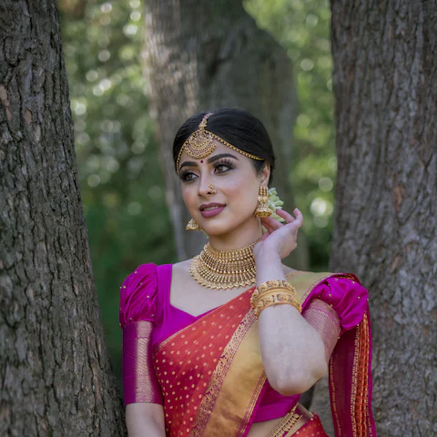 Woman in a pink and orange pattu saree with gold jewellery