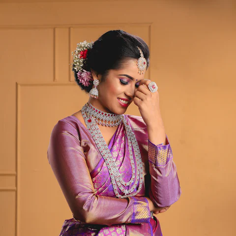 Woman in a purple and gold silk saree with flowers in her hair
